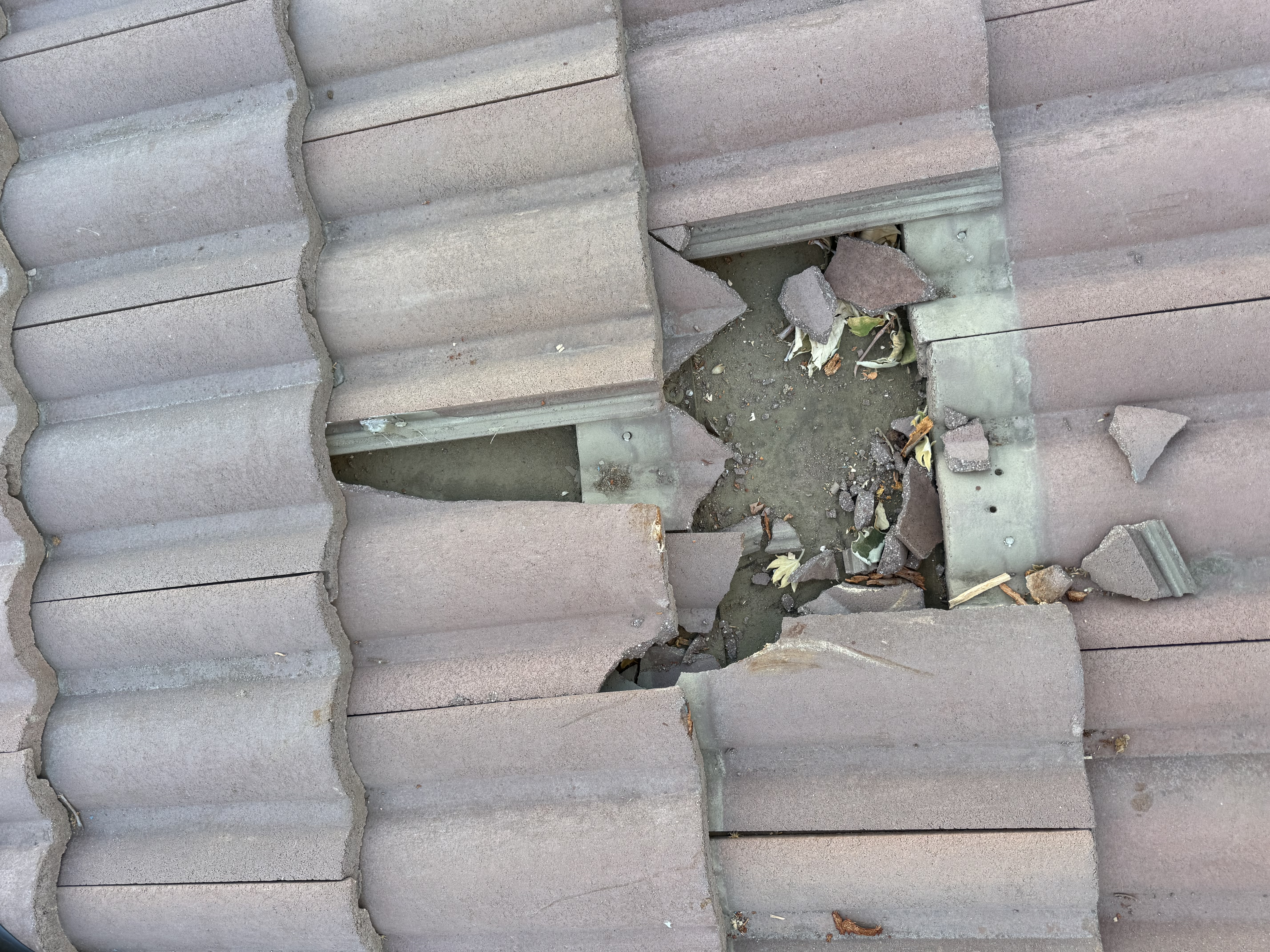 Broken tile exposing underlayment with debris