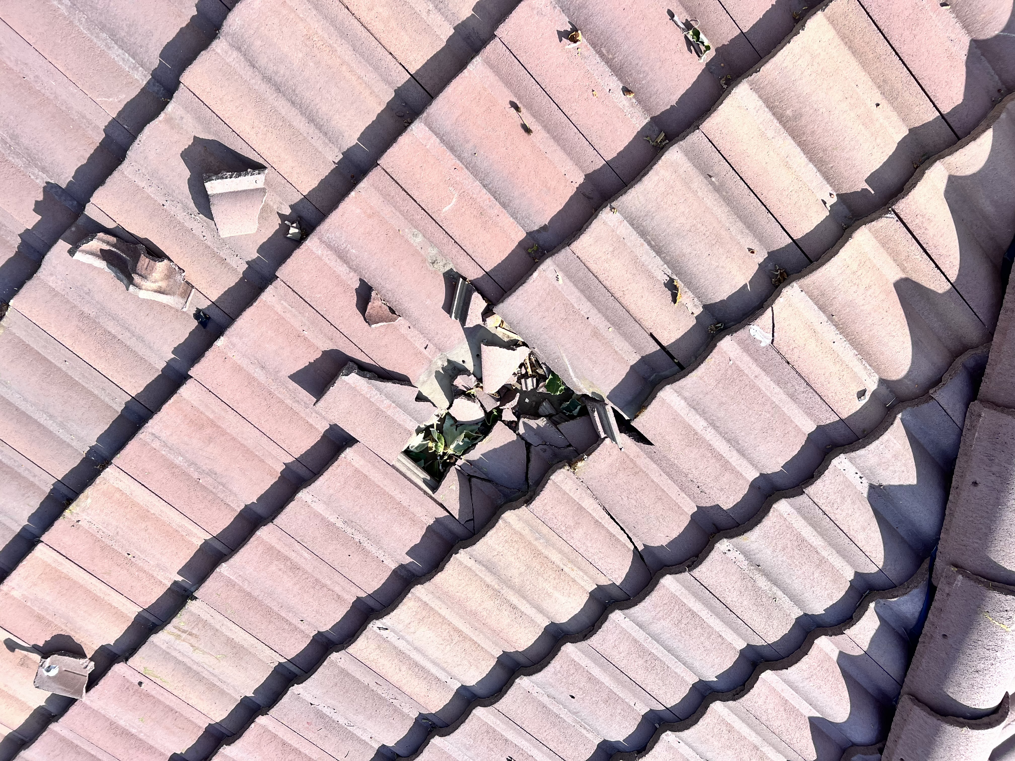 Shattered roof tiles with hole and debris